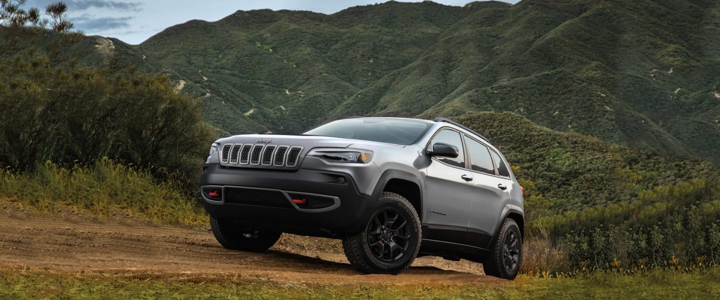 A gray 2020 Jeep Cherokee Trailhawk parked on a mountainous dirt path.