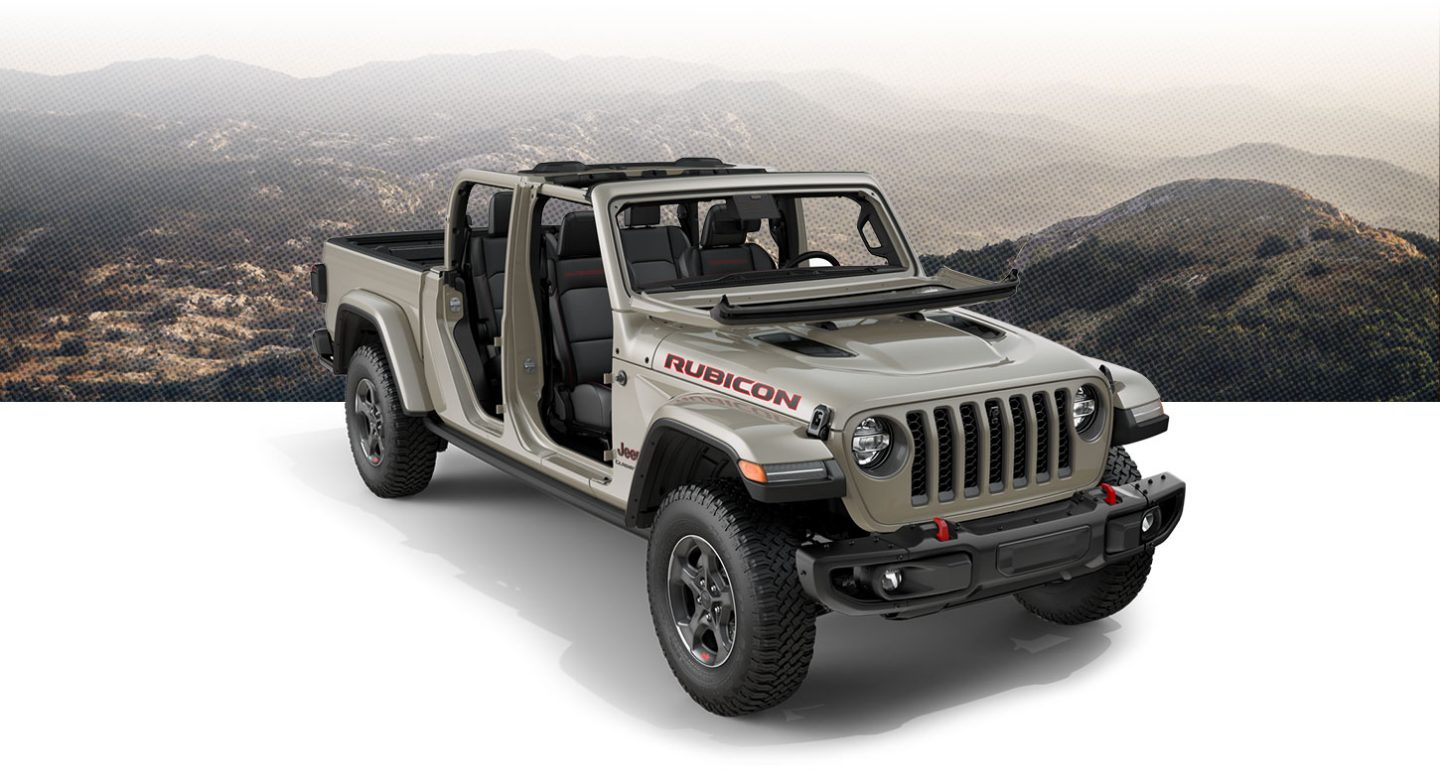 Tan gladiator with windshield down posed in front of mountainous background
