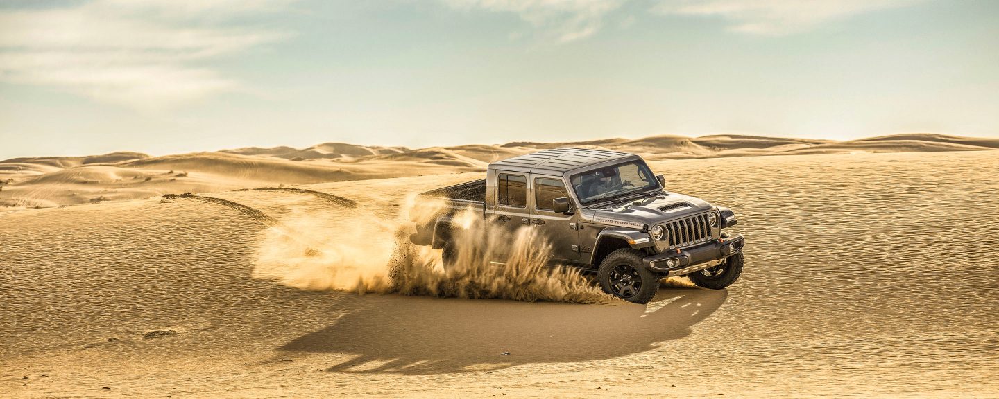Mojave. A 2022 Jeep Gladiator Mojave being driven on sand in the desert, with the 4x4 Desert Rated logo superimposed overhead.