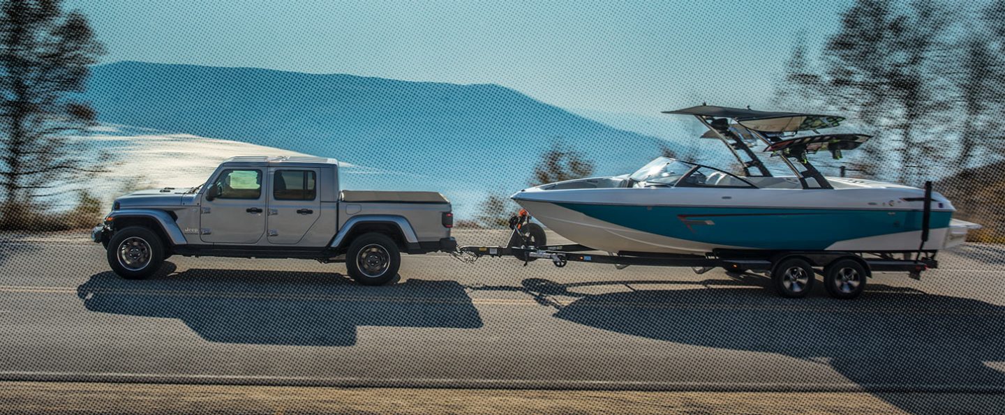 Grey gladiator driving on a highway towing a boat