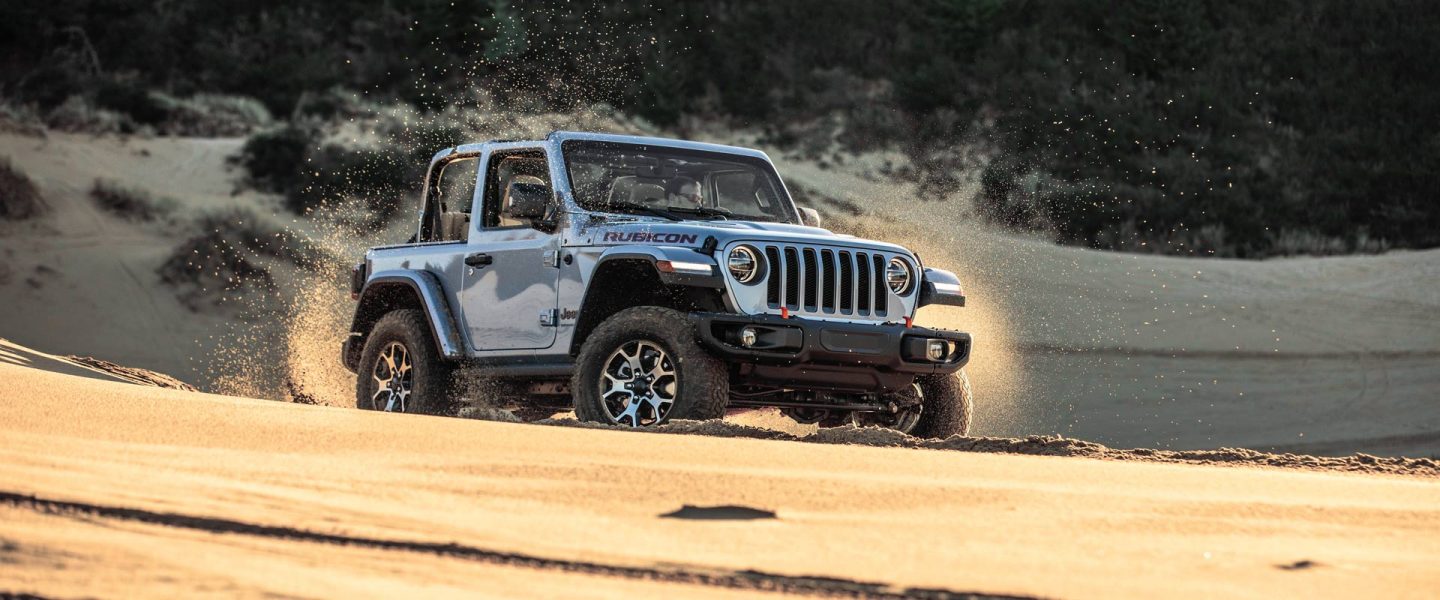 A head-on view of the 2021 Jeep Wrangler Sahara against a mountain backdrop.