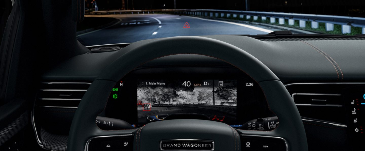 The driver information cluster display in the 2023 Grand Wagoneer Series III, displaying a night vision view of the road ahead with potential obstacles highlighted in red.